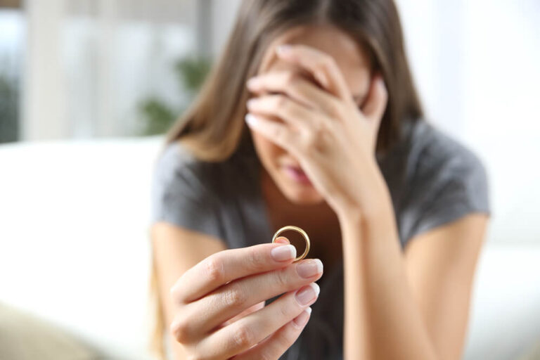 Women holding her wedding ring with her other hand covering her face