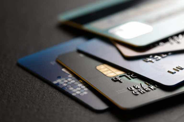 A pile of credit cards on a black surface, with various cards showing different logos.