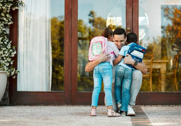 man hugging two children on doorstep of home