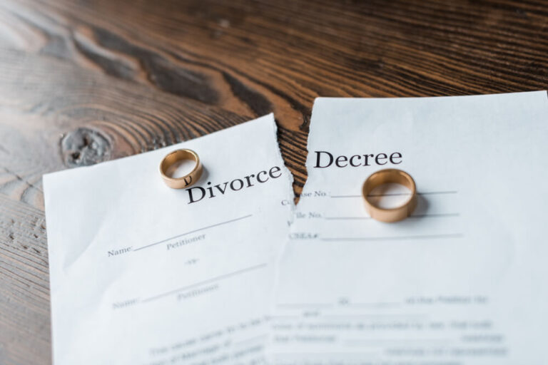 A divorce decree ripped in half with a wedding band on each piece of the decree