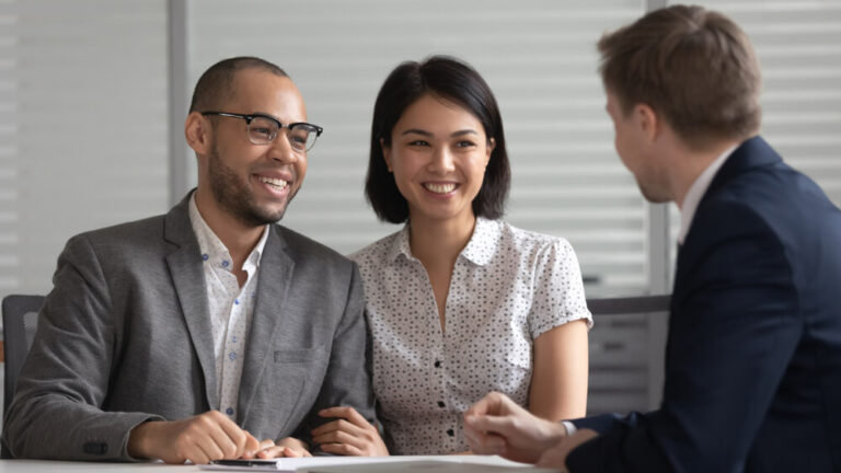 A couple sitting at a table with a lawyer talking about the paperwork in front of them