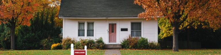 a house with a foreclosure sign on the front lawn