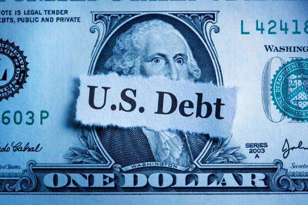 A U.S. dollar bill with a torn paper labeled "U.S. Debt" obscures part of George Washington's face, symbolizing the financial strain that might lead one to wonder, "How much debt do you need to file Chapter 7?" as they seek relief from overwhelming obligations.