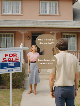 A man and woman standing in front of a house with a for sale sign.