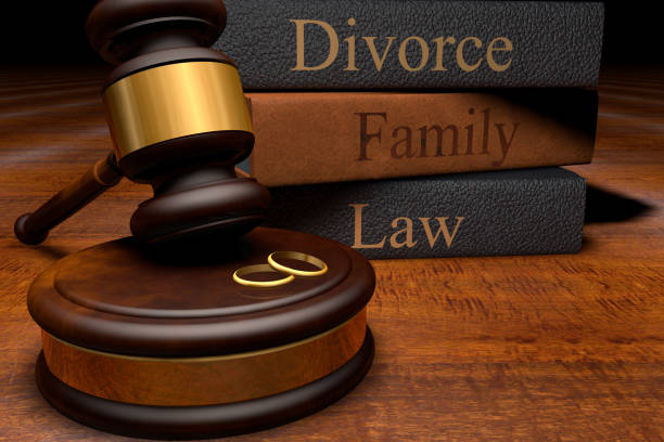 Gavel, divorce law books and wedding rings on wooden desk