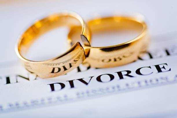 Two broken golden wedding rings divorce decree document. Divorce and separation concept