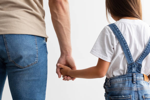 Trust And Support Concept. Cropped close up of man and girl holding hands, enjoying spending free time together, isolated over white studio background. Love And Family Care