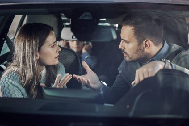 Frustrated parents arguing while traveling with their son in car. The view is through windshield.