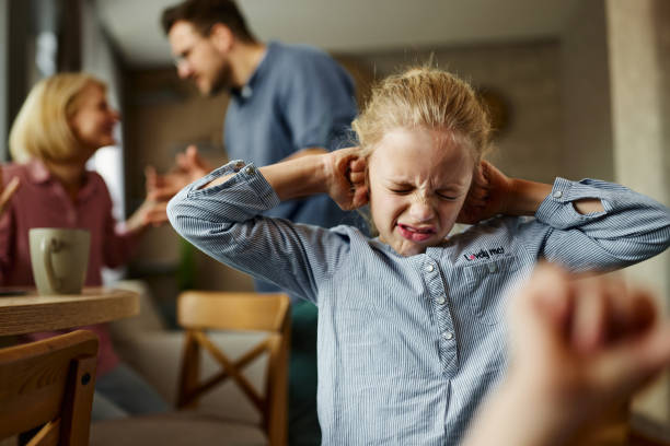 Displeased little girl refusing to listen to her parents arguing at home.