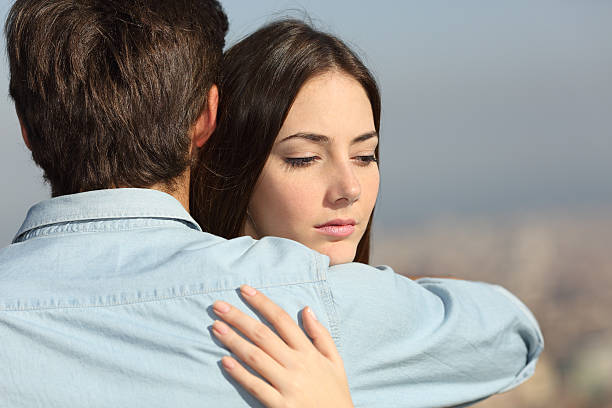 Sad woman hugging her boyfriend and looking down couple problems concept