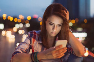 Unhappy woman texting at the bridge