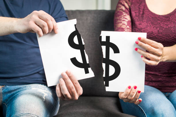 Fight about money or financial argument concept. Man and woman holding ripped paper with dollar sign.