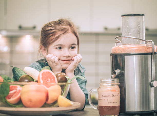 little cute happy girl preparing juice fresh in the kitchen, concept of healthy baby food and happy family