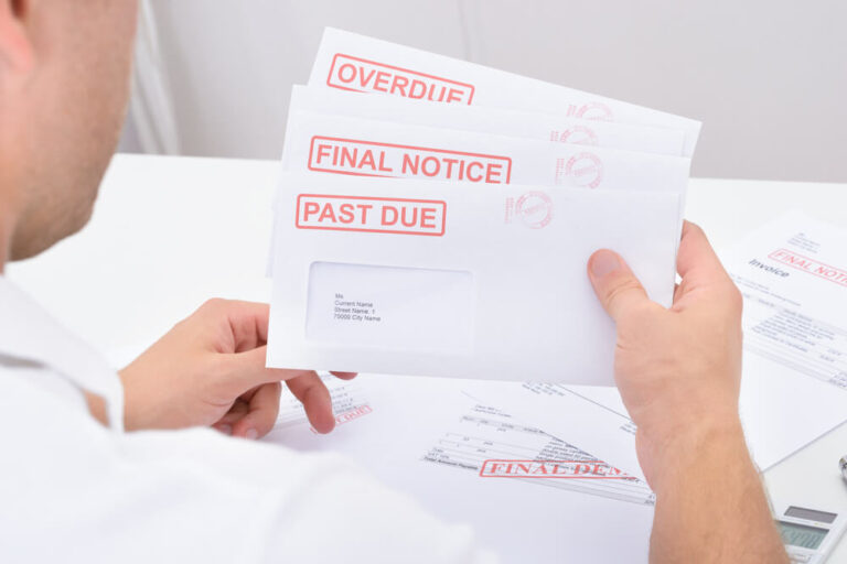 A man looking at many different envelopes that say, overdue, final notice and past due