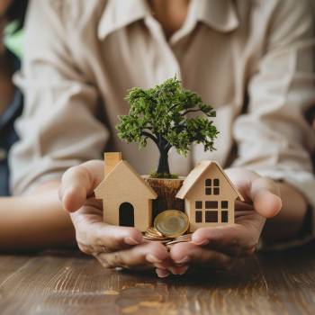 a person holding a house, some coins, and a tree in his hands looking at beneficiary designations for his estate