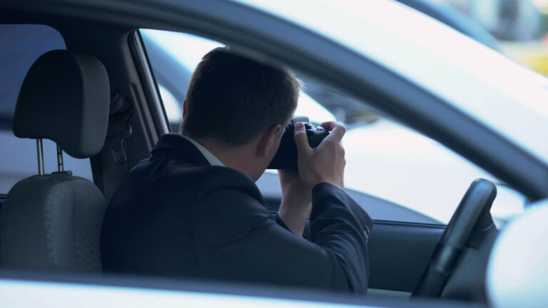 An image of a private investigator taking pictures from his car