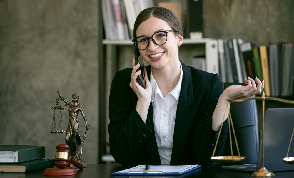 Portrait of young female Lawyer or attorney working in the office, using mobile phone, smiling and looking at camera.