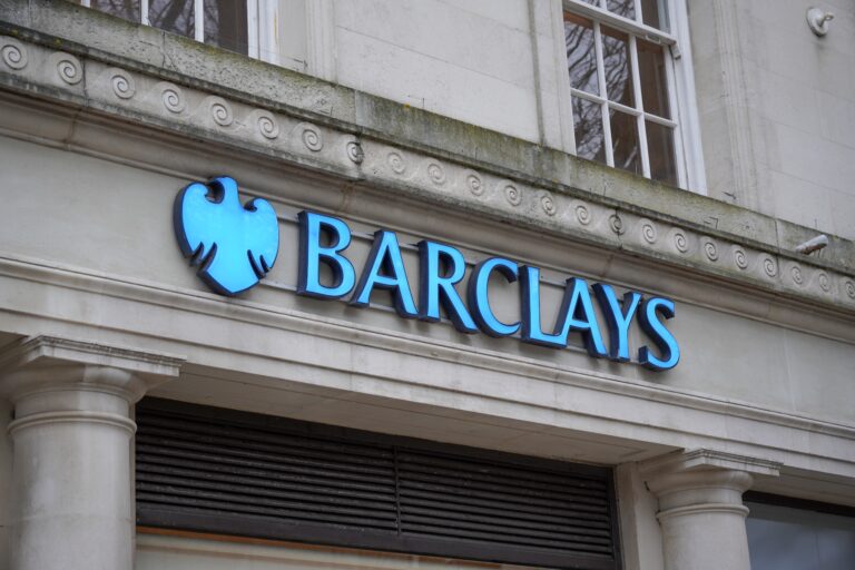 The exterior of a Barclays bank with a blue logo on a stone building facade.