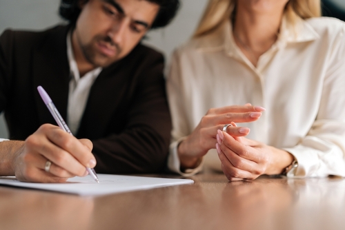 Cropped shot of sad spouses couple signing decree papers getting divorced in lawyers office at desk. Unhappy married man and woman filing divorce, shares or mortgage assets with attorney.