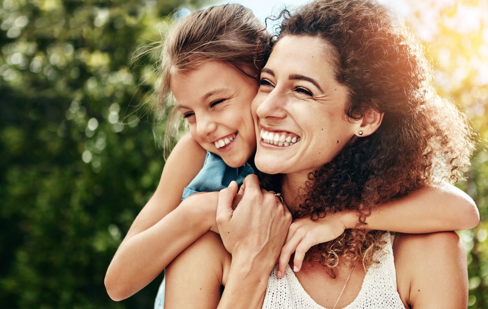 Happy, woman and child hug outdoor with bonding, care or support for security trust at family home backyard. Smile, mother and girl for embrace moment, love and sunshine vacation of childhood memory