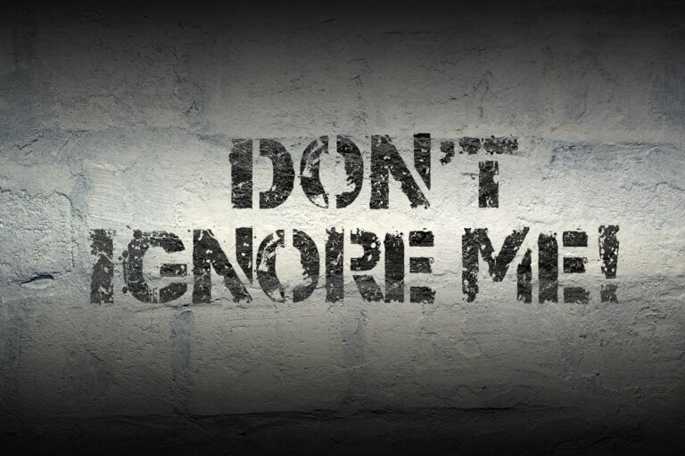 Text "DON'T IGNORE ME!" spray-painted in black on a white brick wall.