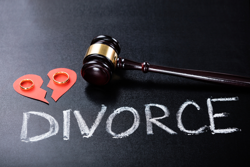 A gavel and two wedding rings rest on a broken heart cutout beside the word "Divorce" in chalk, prompting thoughts about whether mediation is required for divorce in Texas.