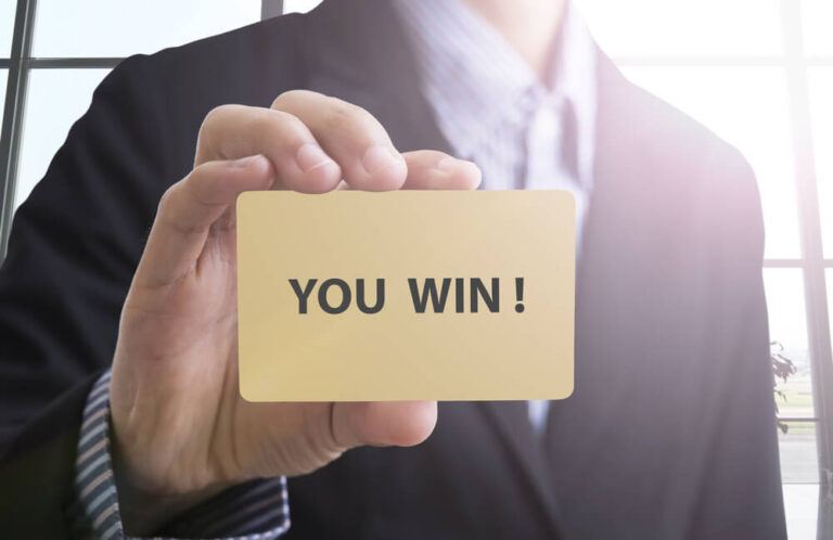 A business man holding up a card that says you win!