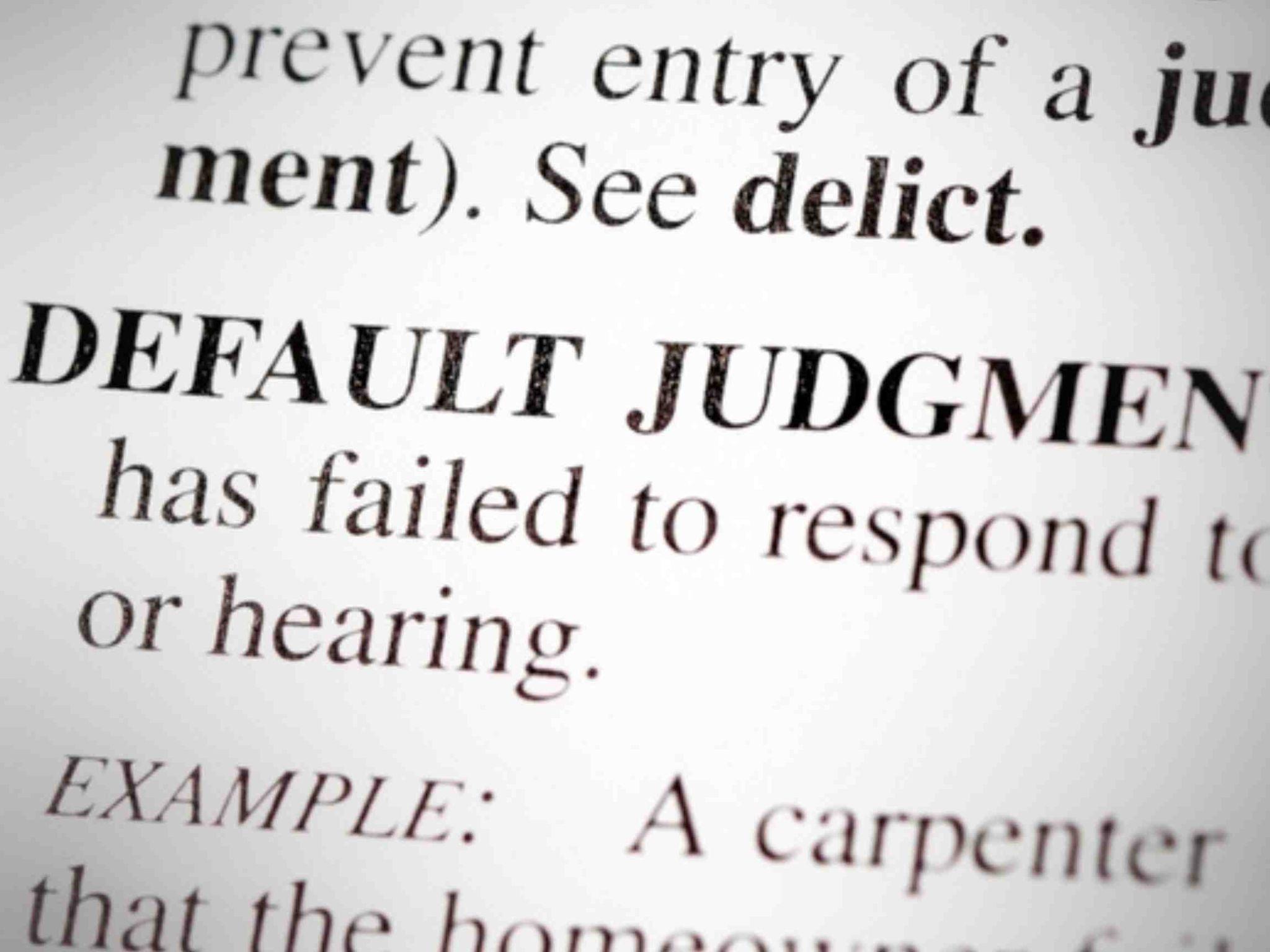 Close-up of a dictionary page showing the term "Default Judgment" and part of its definition, hinting at the consequences of not responding in legal matters, much like what happens if you don't sign divorce papers.